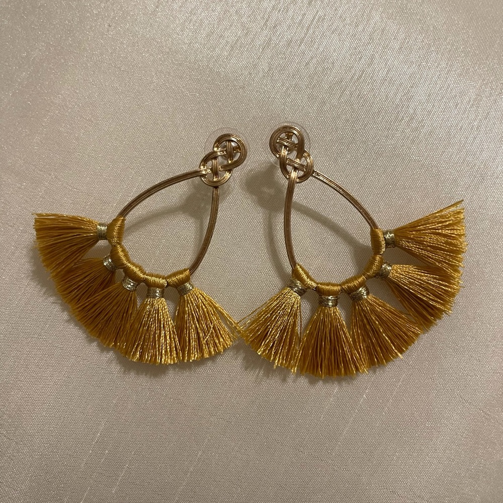 A stylish, never worn pair of fringe, hanging earrings, gold in color.